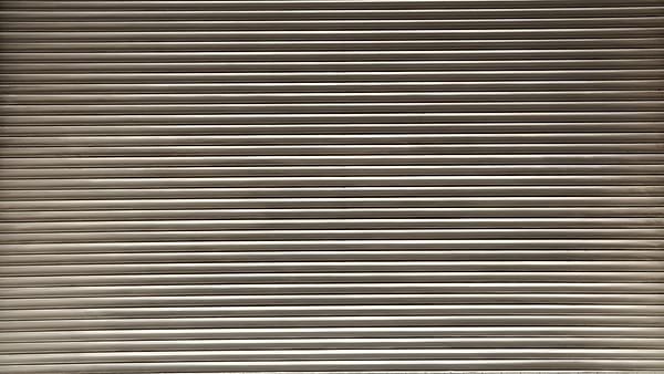 A closed corrugated metal roller shutter filling the frame, its horizontal ribs catching a warm sheen