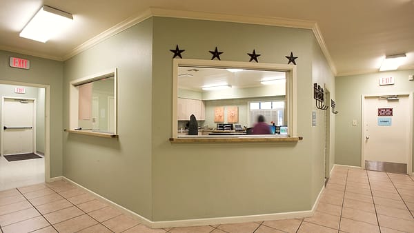 A tiled lobby with a reception window cut into a green wall, four metal stars mounted above it
