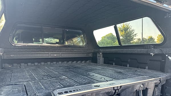 An open pickup bed fitted with sliding storage drawers under a fibreglass canopy.
