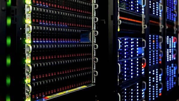A close, straight-on view of dense storage drive bays in a dark room, edged by a bright green column of indicator lights