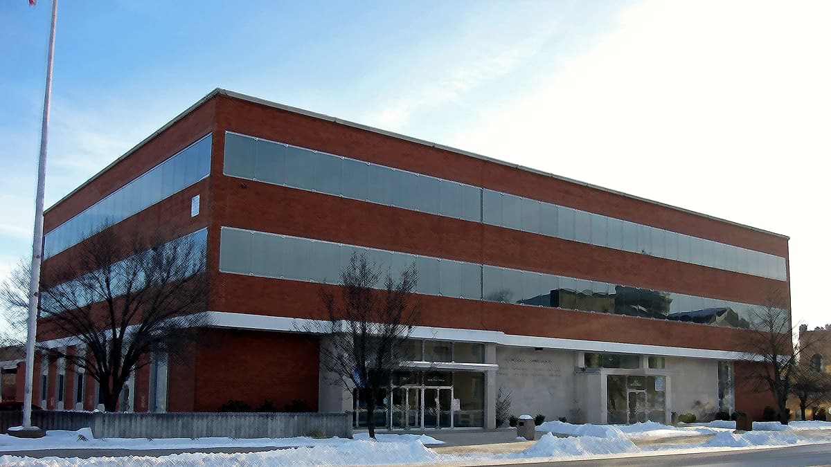 A three-story brick and glass office block with a bare flagpole and snow piled along the curb