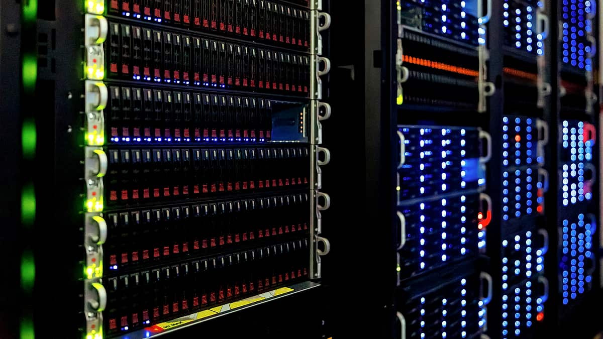A close, straight-on view of dense storage drive bays in a dark room, edged by a bright green column of indicator lights